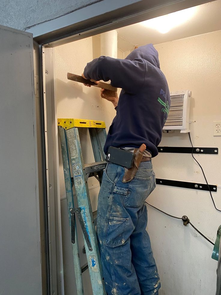 Handyman installing wall hardware on ladder